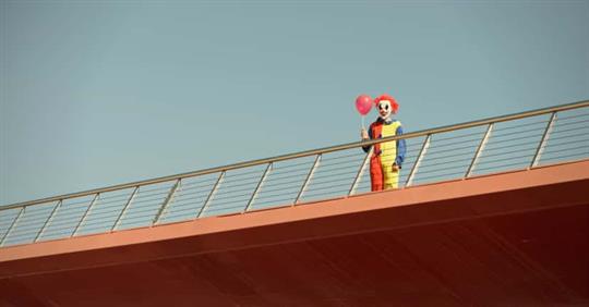 Clown standing on an overpass.